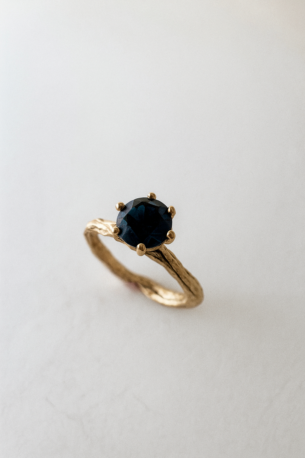 Angled side view of the 10k yellow gold London blue topaz ring highlighting its handcrafted textured band.