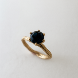 Angled side view of the 10k yellow gold London blue topaz ring highlighting its handcrafted textured band.