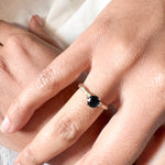 London blue topaz ring in 10k yellow gold worn on a hand, photographed over soft fabric.