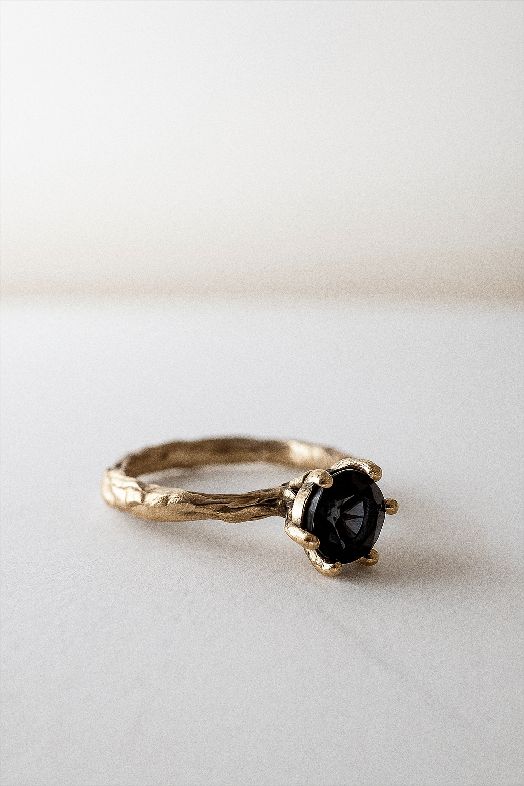 Side profile of the London blue topaz ring in 10k yellow gold resting on a light surface.