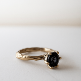 Side profile of the London blue topaz ring in 10k yellow gold resting on a light surface.