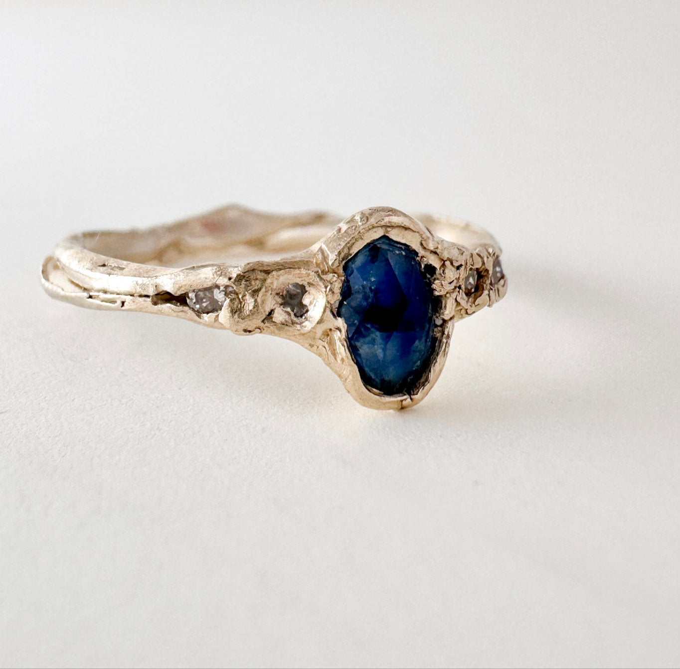 10k yellow gold ring with a Montana sapphire and two lab-grown diamonds set in an organic sculpted band, shown front-facing on a white background.