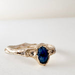10k yellow gold ring with a Montana sapphire and two lab-grown diamonds set in an organic sculpted band, shown front-facing on a white background.