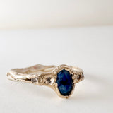 10k yellow gold ring with a Montana sapphire and two lab-grown diamonds set in an organic sculpted band, shown front-facing on a white background.