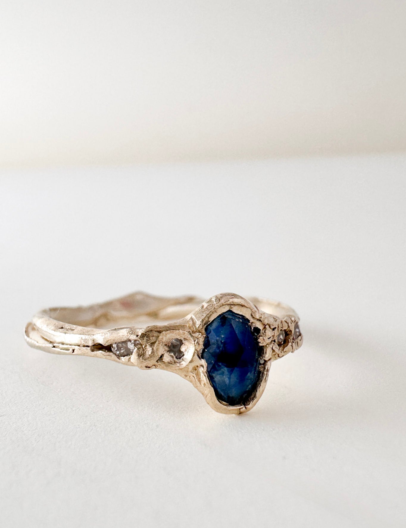 10k yellow gold ring with a Montana sapphire and two lab-grown diamonds set in an organic sculpted band, shown front-facing on a white background.