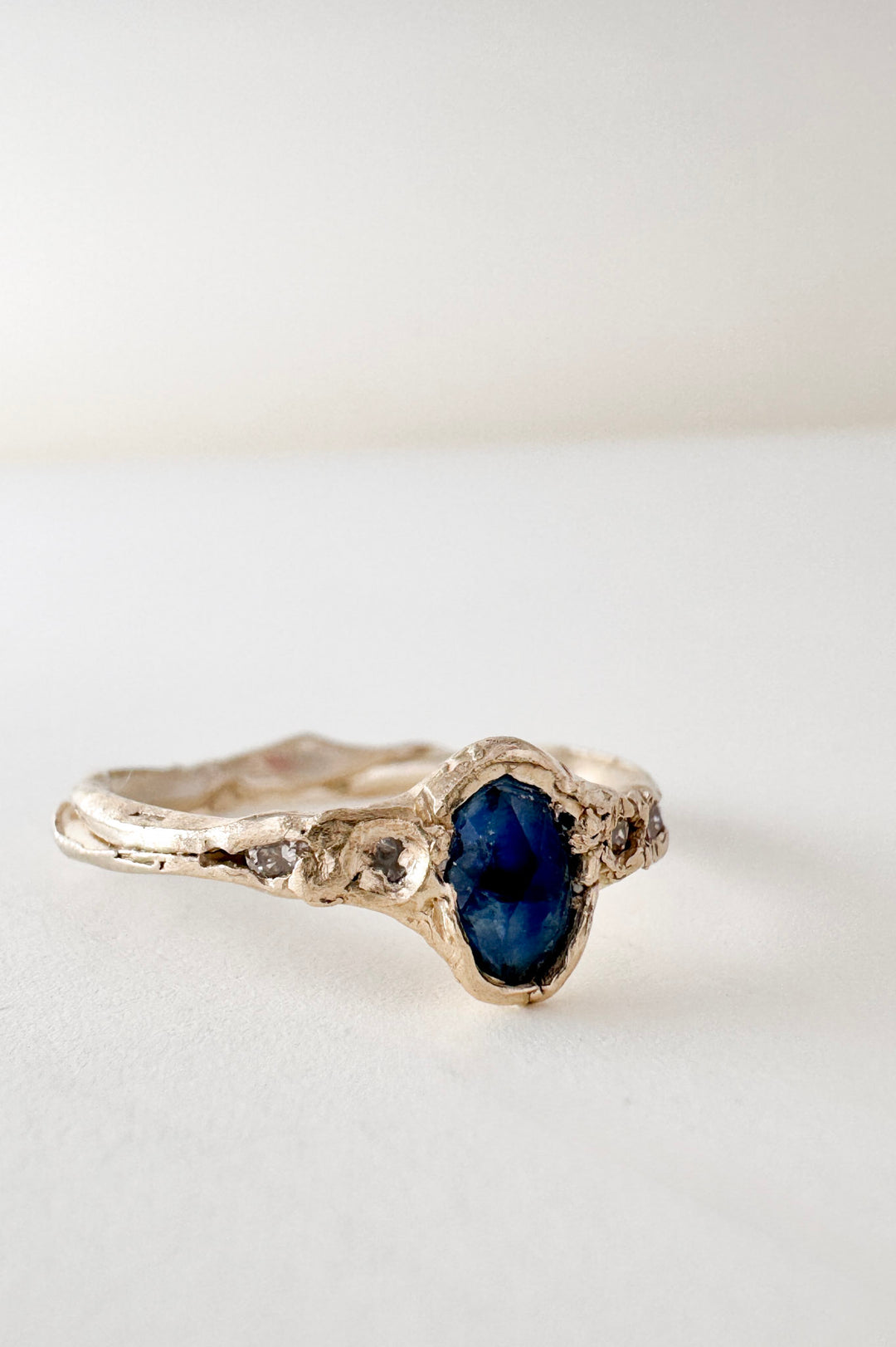 10k yellow gold ring with a Montana sapphire and two lab-grown diamonds set in an organic sculpted band, shown front-facing on a white background.