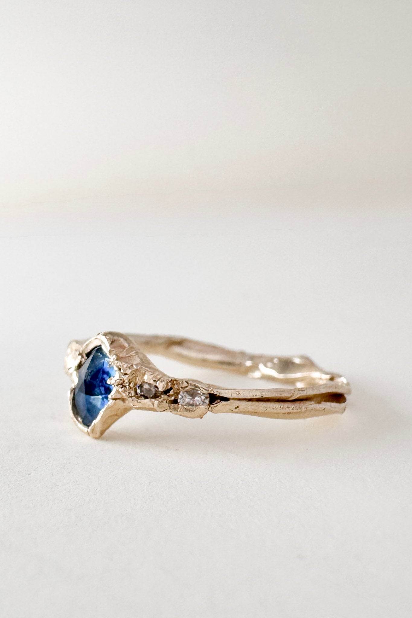Angled side view of the 10k yellow gold ring highlighting the Montana sapphire and lab-grown diamonds along the textured band.