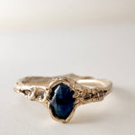 Side-front view of the 10k yellow gold Montana sapphire ring with lab-grown diamonds, displayed on a light surface.