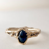 Side-front view of the 10k yellow gold Montana sapphire ring with lab-grown diamonds, displayed on a light surface.