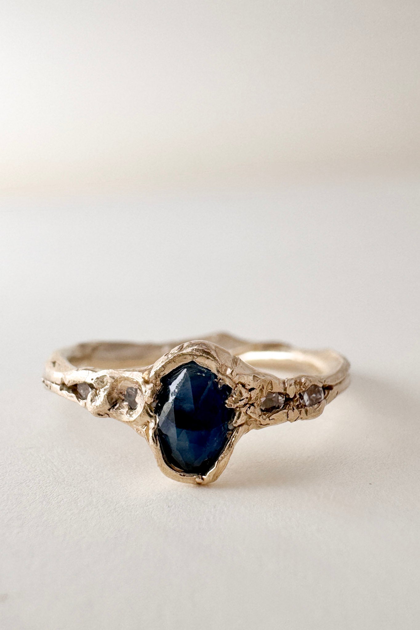 Side-front view of the 10k yellow gold Montana sapphire ring with lab-grown diamonds, displayed on a light surface.