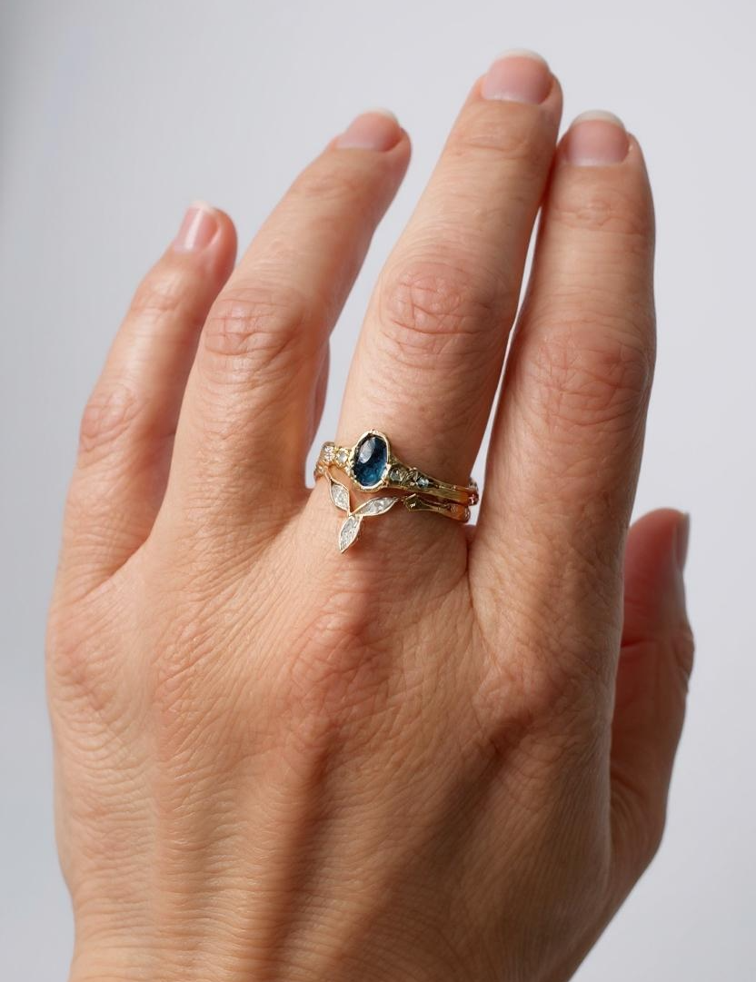 Montana sapphire and lab-grown diamond ring in 10k yellow gold worn on a hand, photographed against a light neutral background.