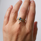 Montana sapphire and lab-grown diamond ring in 10k yellow gold worn on a hand, photographed against a light neutral background.