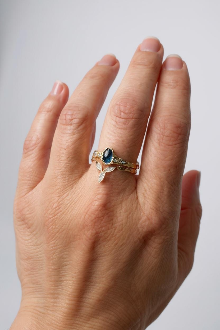 Montana sapphire and lab-grown diamond ring in 10k yellow gold worn on a hand, photographed against a light neutral background.