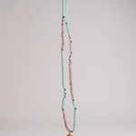 Orange Necklace laid out vertically on grey, showing its full strand of alternating mint-green and pink beads and the bright orange crescent moon pendant at the bottom