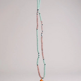 Orange Necklace laid out vertically on grey, showing its full strand of alternating mint-green and pink beads and the bright orange crescent moon pendant at the bottom