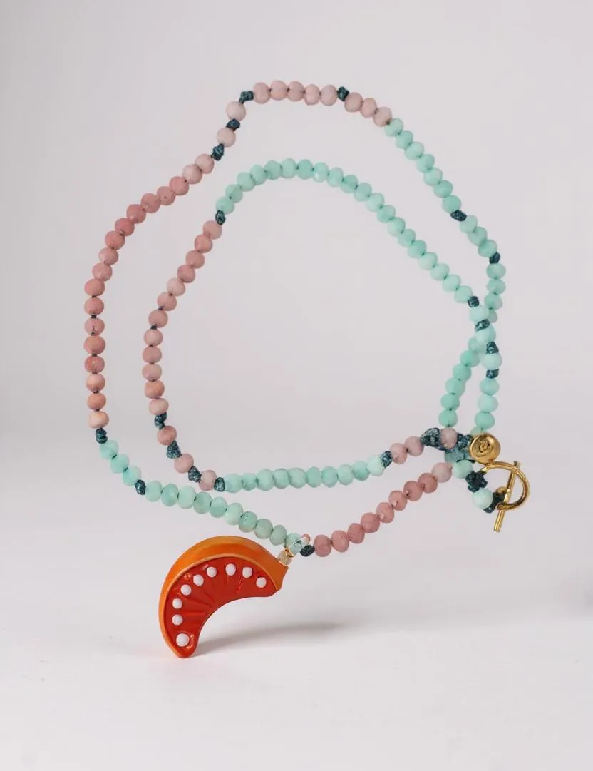 “Flat lay of Orange Necklace on a white background, showing alternating mint‑green and pink beads with a bright orange crescent pendant.