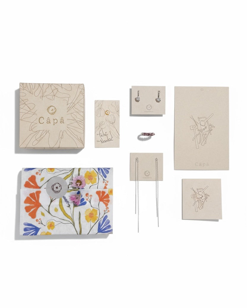 Collection of Capá stationery items including notebooks, a card, and a keychain on a white background.