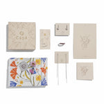 Collection of Capá stationery items including notebooks, a card, and a keychain on a white background.