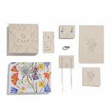 Collection of Capá stationery items including notebooks, a card, and a keychain on a white background.