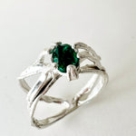 Sterling silver ring with a lab-grown emerald set in an organic sculpted band, shown front-facing on a neutral background.