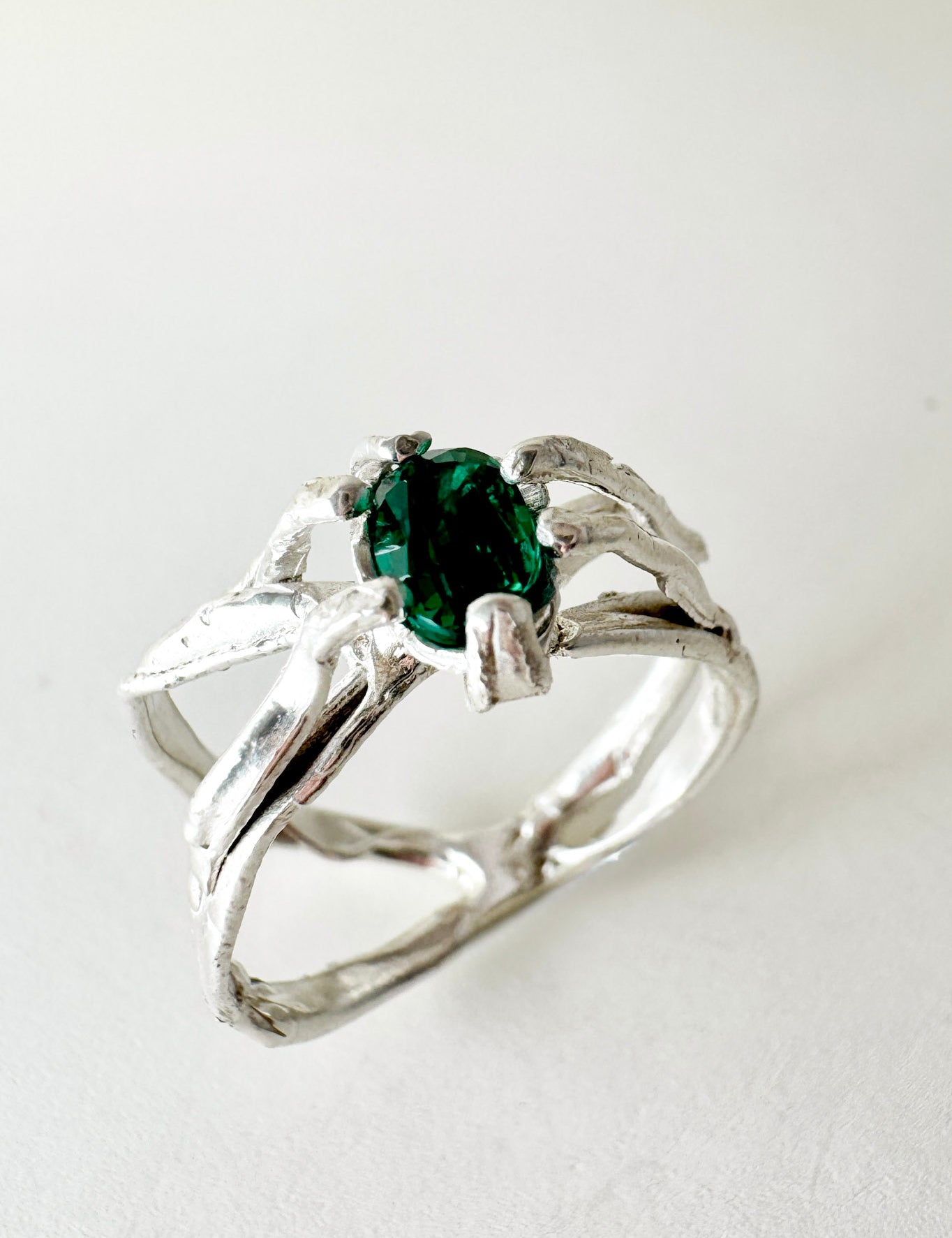 Sterling silver ring with a lab-grown emerald set in an organic sculpted band, shown front-facing on a neutral background.