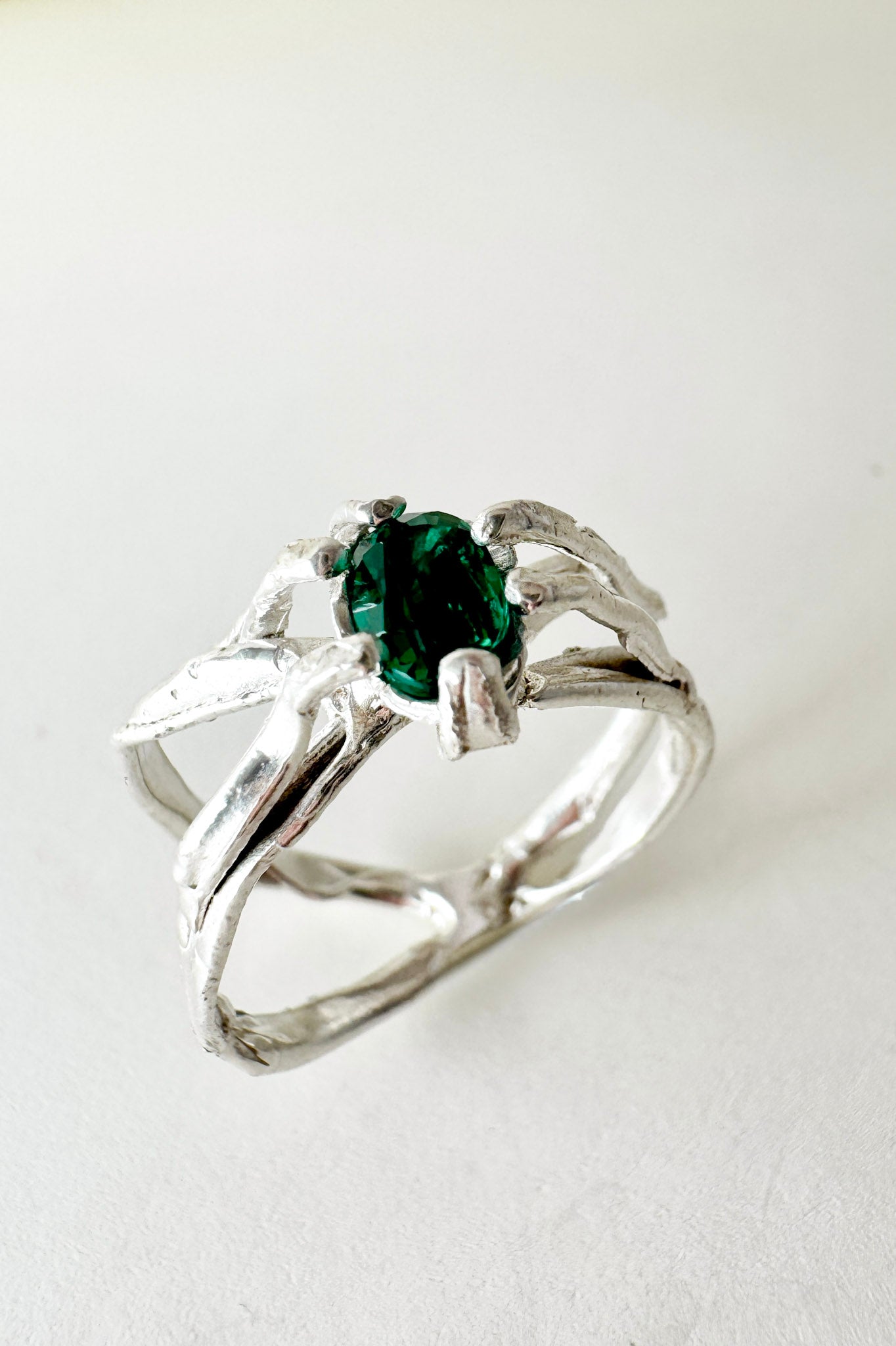 Sterling silver ring with a lab-grown emerald set in an organic sculpted band, shown front-facing on a neutral background.