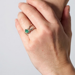 Lab-grown emerald sterling silver ring worn on a hand, photographed against a light grey wall.