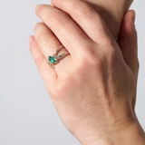 Lab-grown emerald sterling silver ring worn on a hand, photographed against a light grey wall.