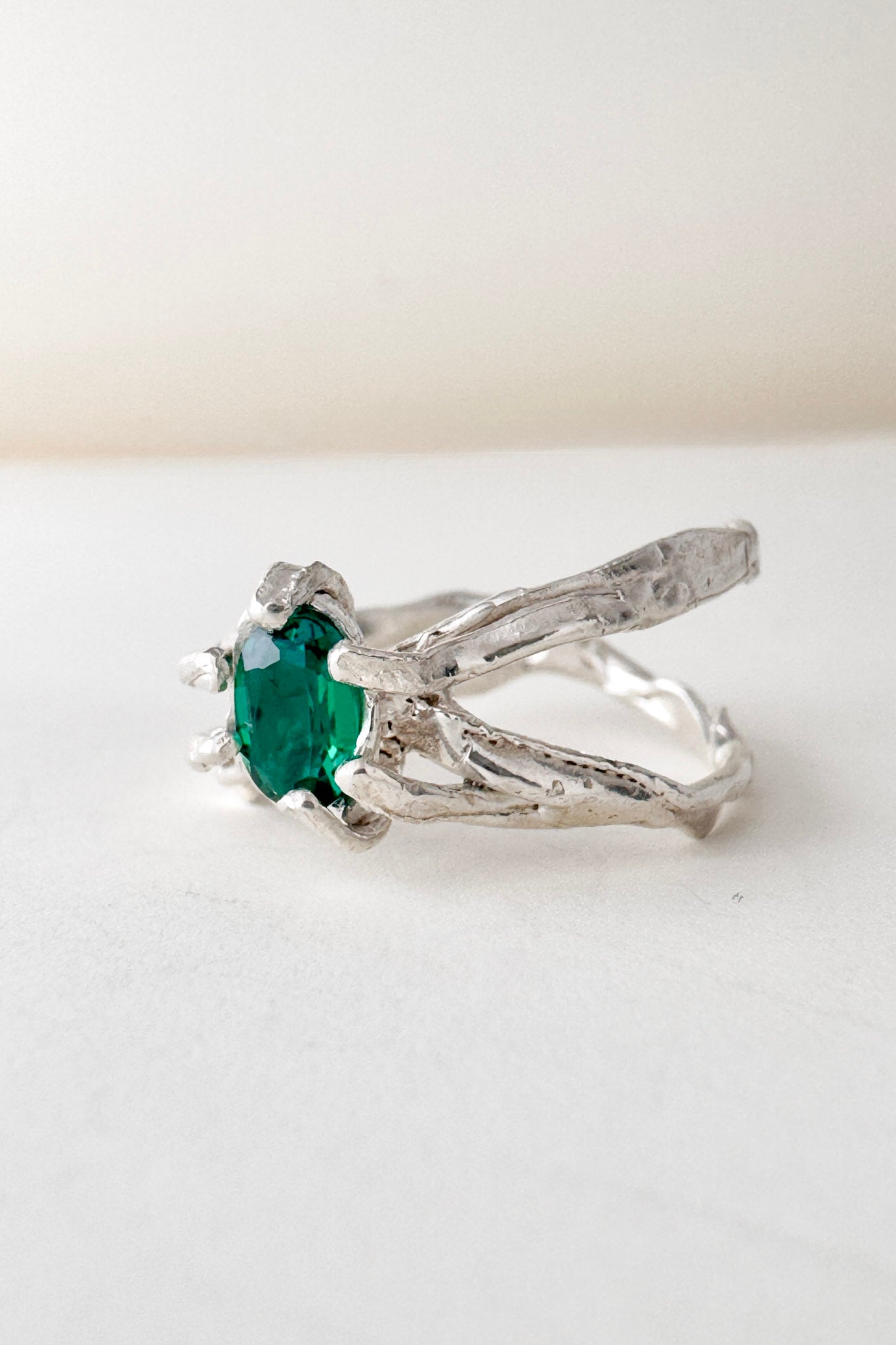 Angled side view of the sterling silver ring with lab-grown emerald, highlighting the textured handmade band.