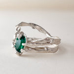 Front-angled view of the sterling silver ring with a vivid green lab-grown emerald, placed on a white surface.