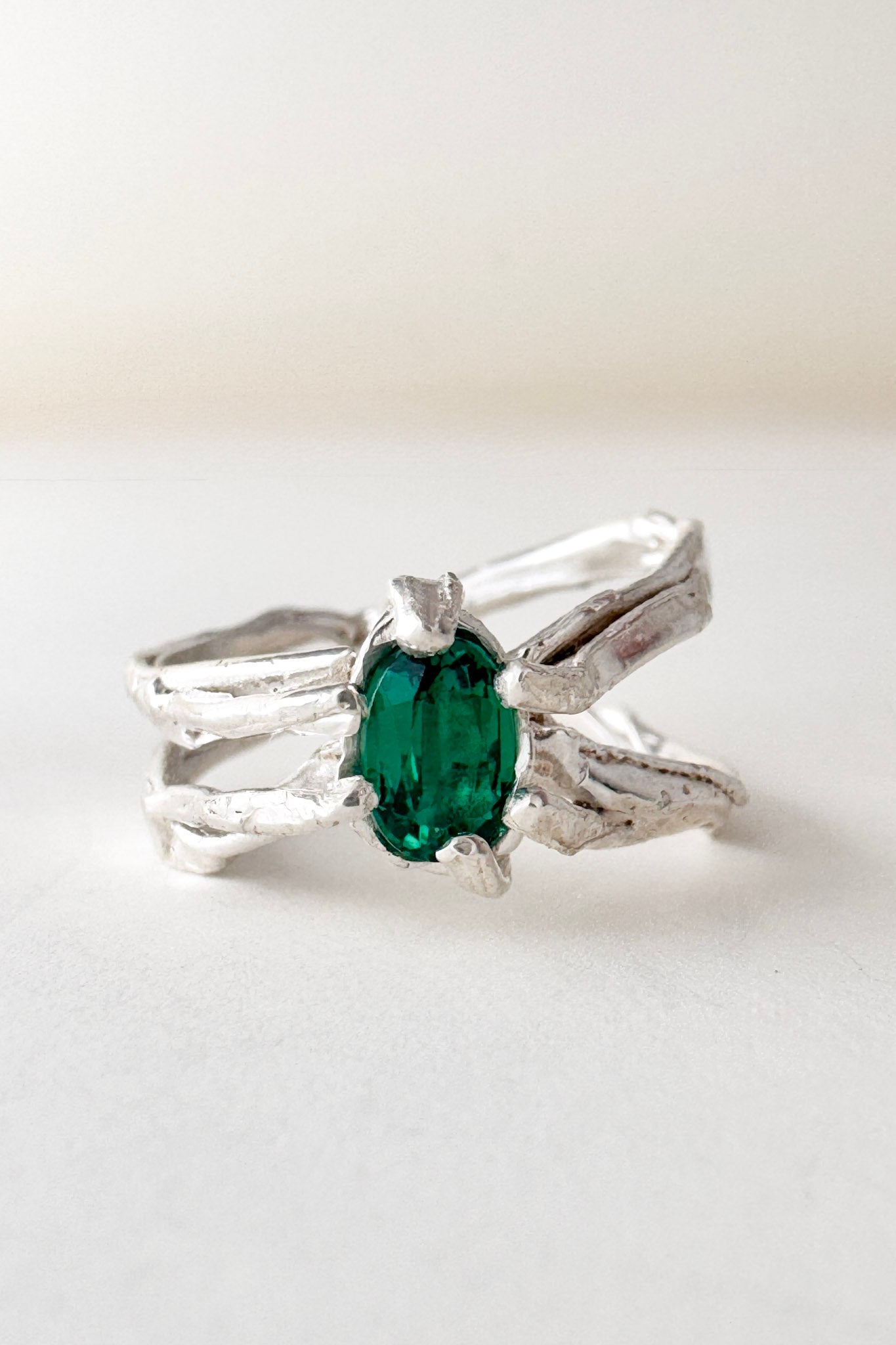 Top-down view of the sterling silver ring featuring a lab-grown emerald and sculpted organic band.