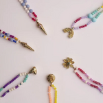 Colorful beaded necklaces with various pendants on a light background