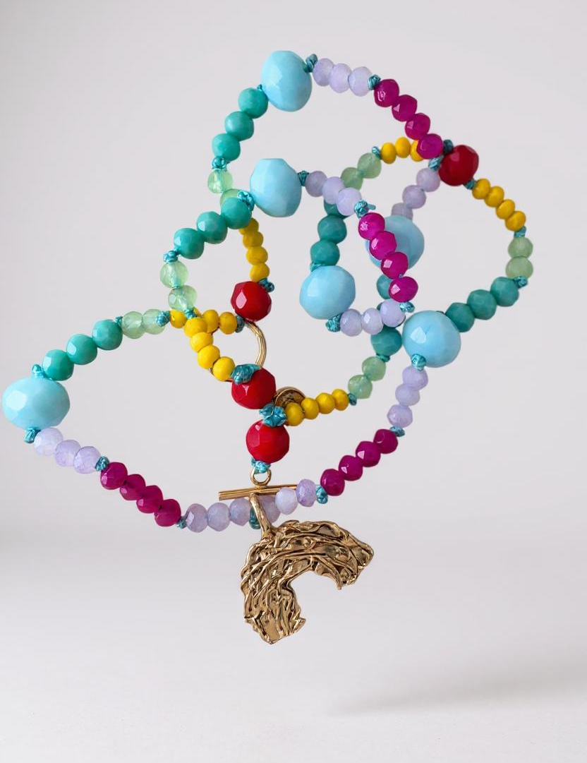Multicolored crystal bead necklace with a gold rainbow-shaped charm on a white background.