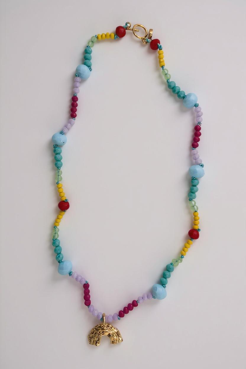 Colorful beaded necklace with a gold charm on a light gray background