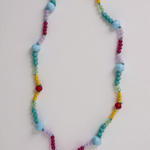 Colorful beaded necklace with a gold charm on a light gray background