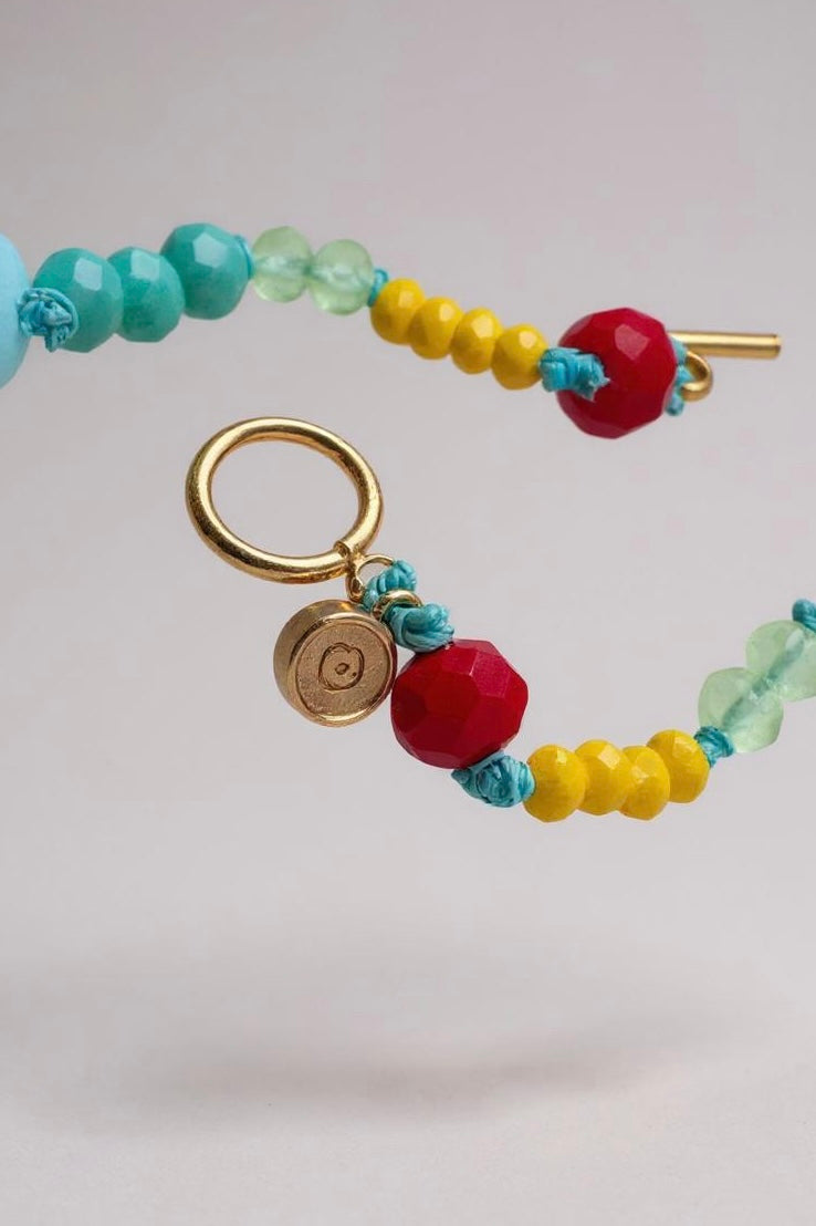 colored bead necklace with gold clasp on a light background.