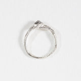 Top view of a silver ring with a hammered band and a raised, irregular stone detail.