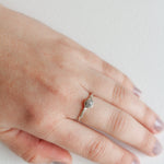 Hand wearing a silver ring with a central textured stone, showcasing its delicate and organic design.