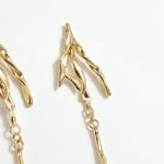 Detail of the upper design of the Root Earrings, showing textured golden branches in gold-plated brass.