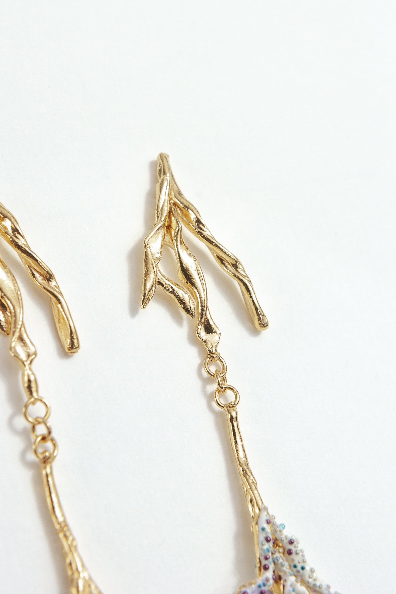 Detail of the upper design of the Root Earrings, showing textured golden branches in gold-plated brass.