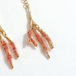 Close-up detail of the Root Earrings in red, with hand-painted coral-colored glass granulation.