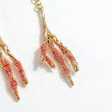 Close-up detail of the Root Earrings in red, with hand-painted coral-colored glass granulation.