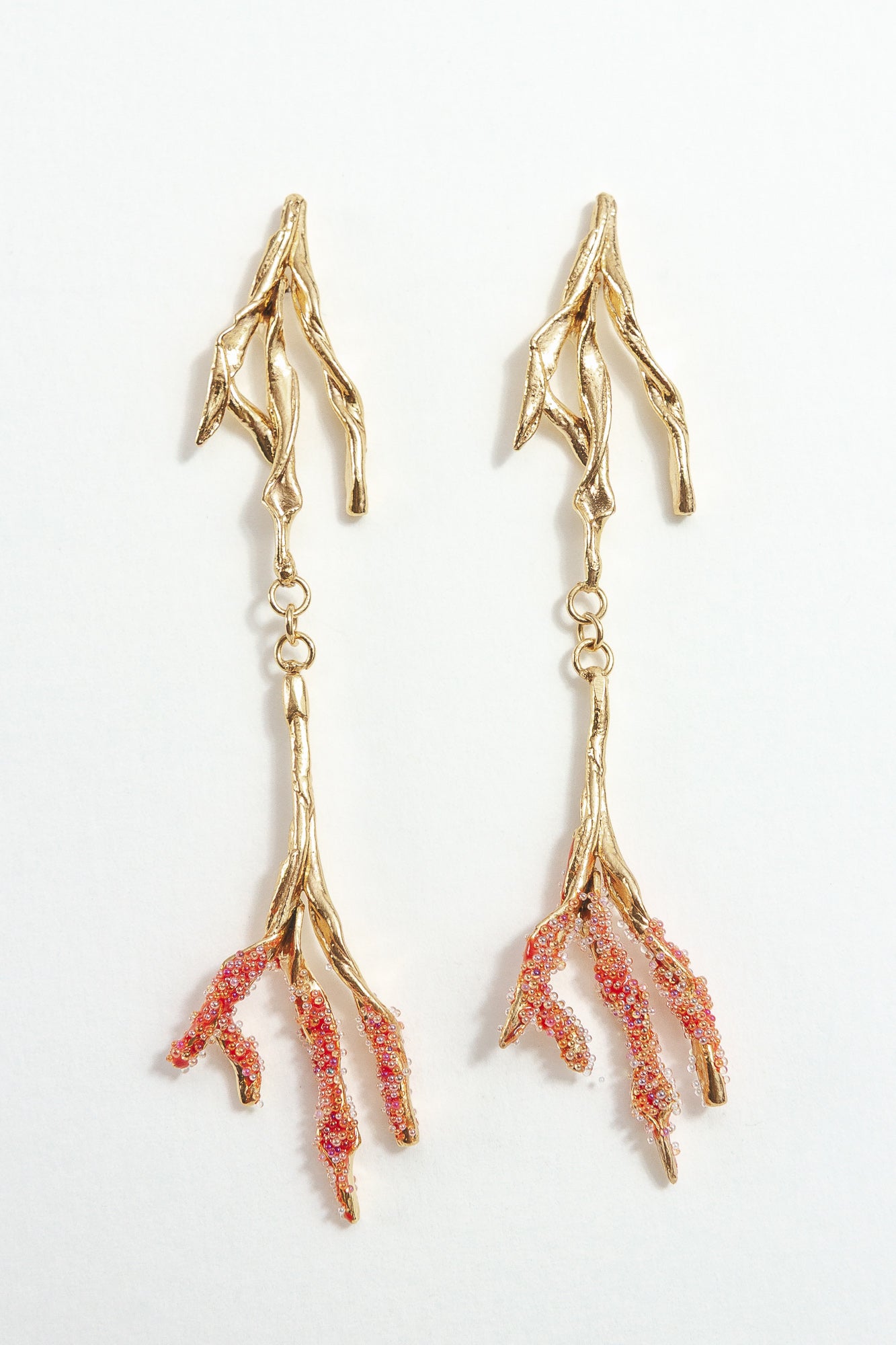 Gold-plated brass Root earrings with textured red tips and glass granulation on a white background.