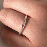 Silver ring with a red gemstone on a finger against a neutral background