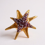 Single gold star-shaped stud earring with purple crystals on a plain white background.