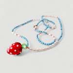 Close-up of the Strawberry Necklace charm: a blown glass strawberry with white dots, handcrafted to give a magical touch to the jewelry.