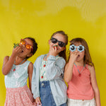 Three young girls standing together against a yellow wall, each wearing the Strawberry Necklace with the pendant hanging at varying heights.