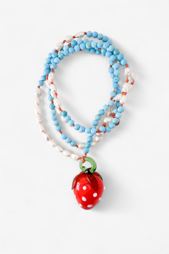 Coiled Strawberry Necklace on a white background, showcasing multiple loops of turquoise and white beads with the red glass strawberry pendant in view