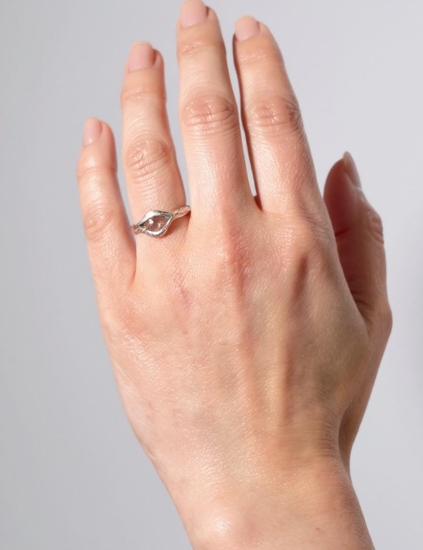 Sterling silver Sunstone ring worn on a hand, photographed against a light grey background.