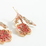 Macro detail of the red elderberry stud earrings highlighting glass granulation, artisanal texture, and coral paint.